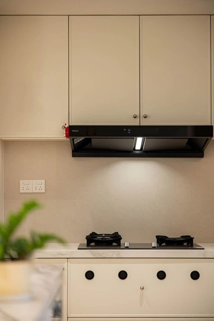 Restored home kitchen with cream cabinets, a gas cooktop, and a range hood, the goal at the end of a long disaster recovery