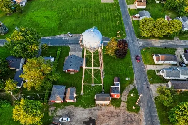 Drone view of shingle roofs on houses around a water tower in an Austin residential neighborhood