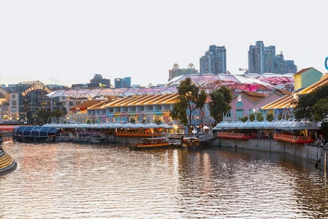 Bumboats moored along the colorful riverside buildings of Clarke Quay at dusk, a boarding area for a Singapore River cruise with kids after a day at Marina Bay