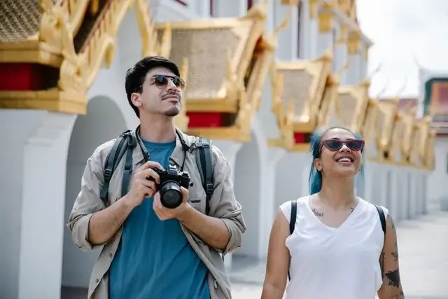 Man and woman sightseeing past golden temple roofs in Thailand, a slow travel date on neutral ground