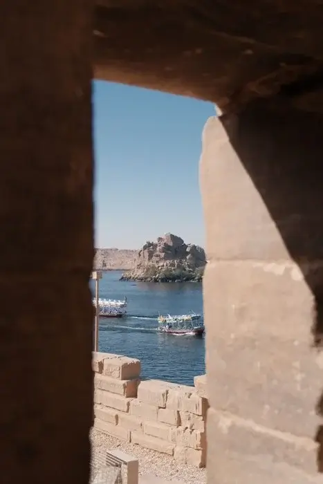 View from Philae Temple of colorful river boats ferrying visitors past granite outcrops near Aswa