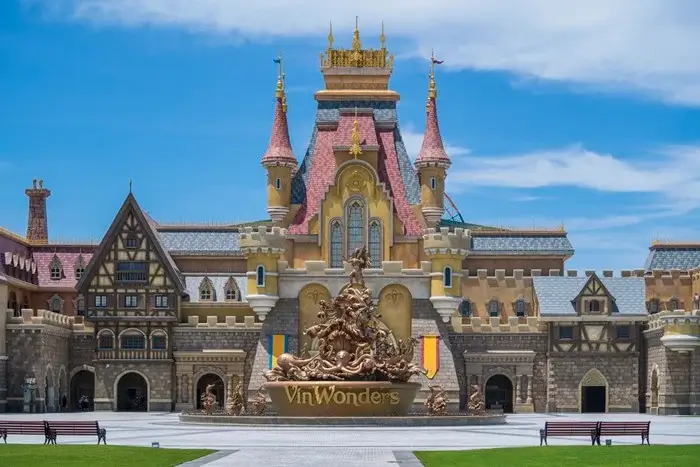 Fairytale castle with pink turrets and a golden fountain at the entrance of VinWonders, a fun family place to visit in Vietnam