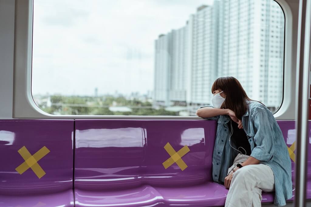 a woman traveling while social distancing on a train. 