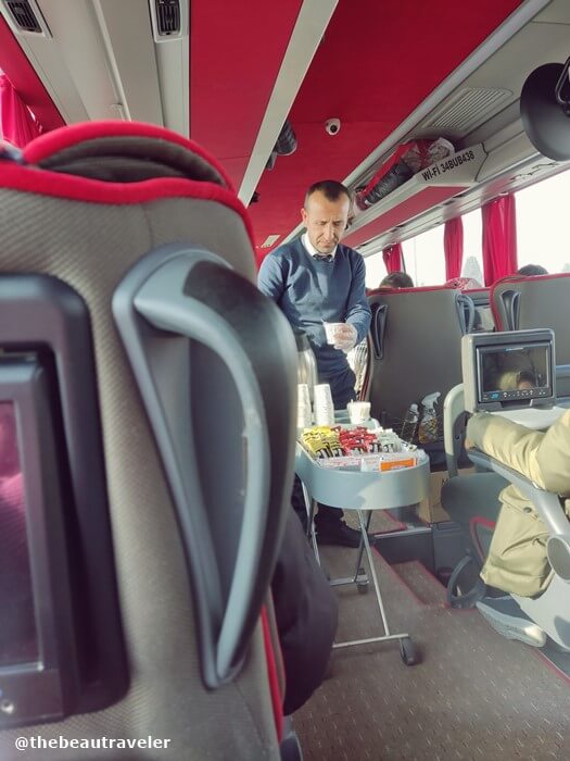 The bus attendant serves snack and drink.