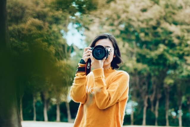 a woman holding a camera to take a snapshot