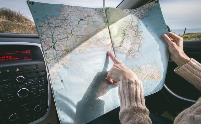 a woman pointing at a map during road trip. 