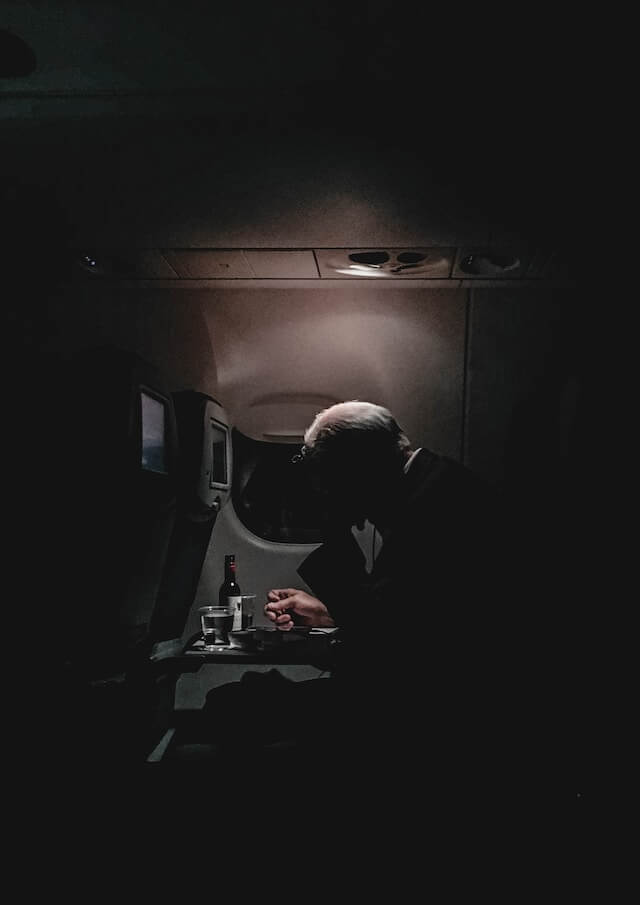 a passenger drinking on an airplane seat. 