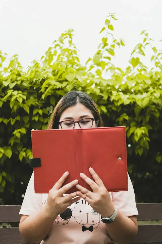 a woman reading while wearing her glasses. 