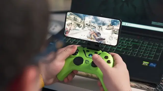 Mobile gaming setup with green controller and smartphone showing action game - popular digital activity ideas for solo travelers seeking entertainment
