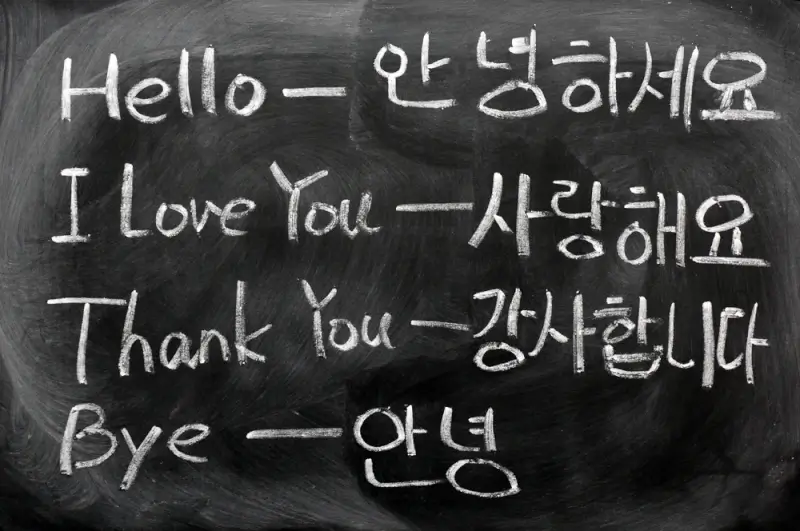 Chalkboard displaying essential Korean language phrases for travelers including Hello, I Love You, Thank You, and Bye with Korean Hangul characters and English translations for basic Korean language learning