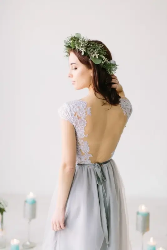 Woman in gray lace wedding guest dress with open back and floral crown, elegant outfit for formal wedding