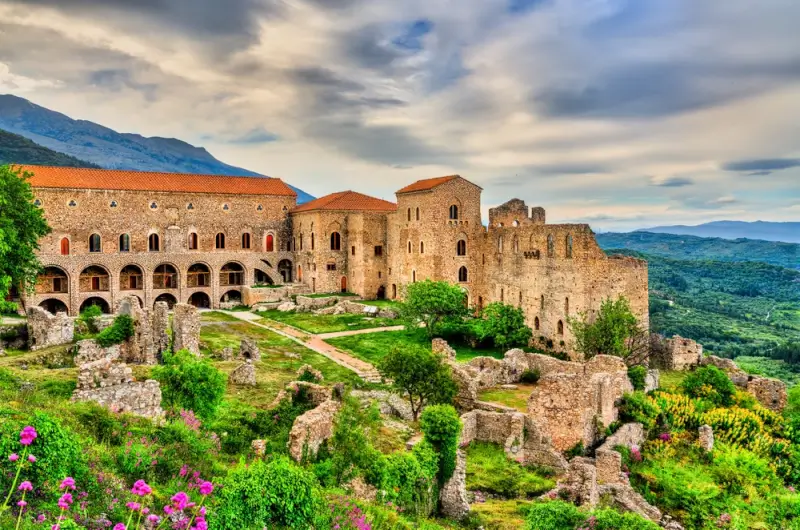 Historic stone castle complex in Peloponnese Greece surrounded by wildflowers and rolling green hills