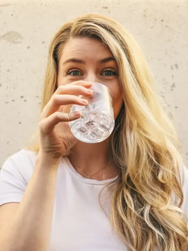 Woman drinking water for hydration showing essential healthy skin tips for glowing complexion