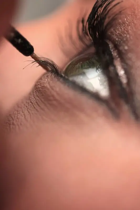 Close-up of mascara wand applying lash growth formula to eyelashes during beauty routine