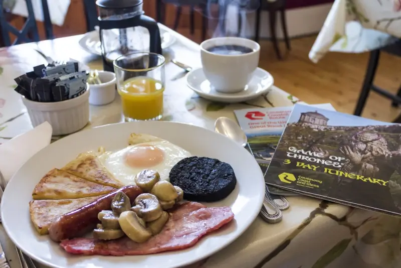Traditional full Irish breakfast with fried egg, black pudding, bacon, sausages, and mushrooms with coffee and orange juice