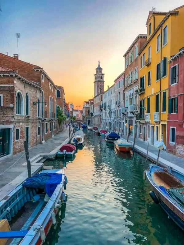 Quiet Venice canal at sunset with colorful houses and moored boats in residential neighborhood