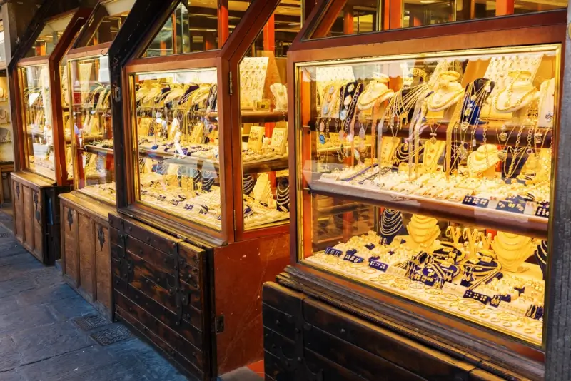 Traditional jewelry shop with illuminated glass display cases showcasing gold necklaces and chains in warm golden lighting