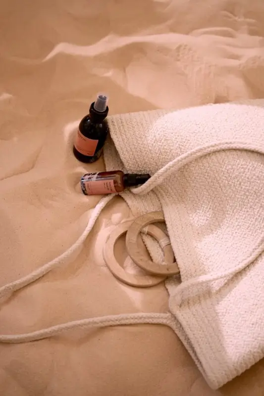 Travel-sized rosemary oil bottles with droppers on soft towels in a tote bag