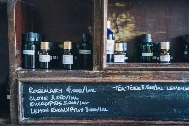 Rosemary oil bottles displayed on rustic wooden shelf with handwritten price labels, perfect for travelers shopping for authentic essential oil benefits at local markets