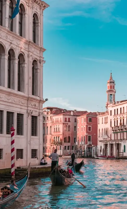 Venetian gondolier navigating canal between historic palazzos and bell tower