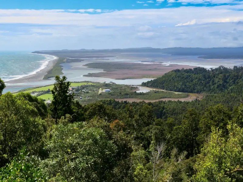 Panoramic view from Auckland's Waitakere Ranges showing pristine beaches, tidal flats and native forest, popular scenic attraction west of the city