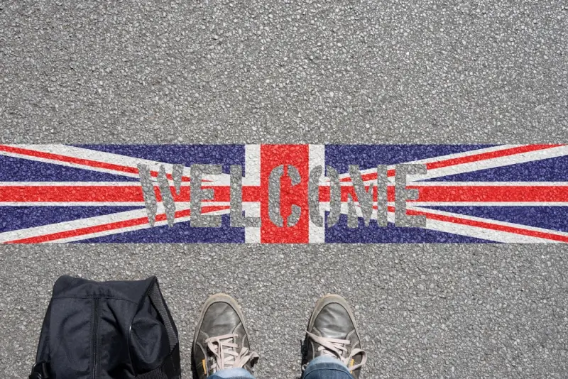 Person standing on UK flag painted on asphalt road with backpack, representing freelancers working legally in the UK