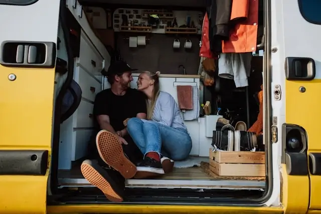 Couple sitting together in yellow van during romantic road trip adventure