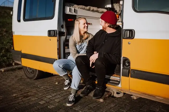 Happy couple sitting on RV steps during romantic road trip getaway