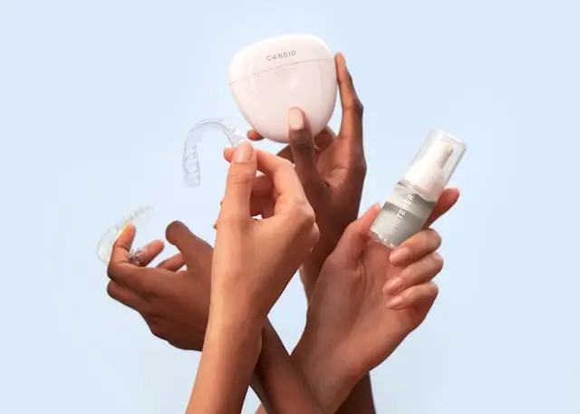 Hands holding dental care products including night guard and oral hygiene items for preventing teeth grinding and dental pain