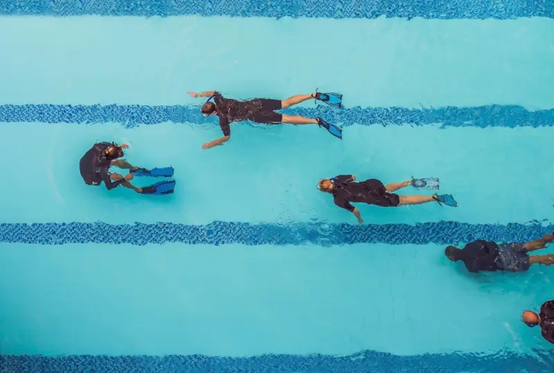 Scuba diving students practicing PADI certification skills in swimming pool during training class