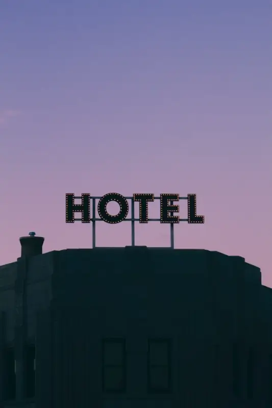 Illuminated hotel sign on rooftop against purple twilight sky representing hospitality and tourism industry establishments creating memorable guest experiences