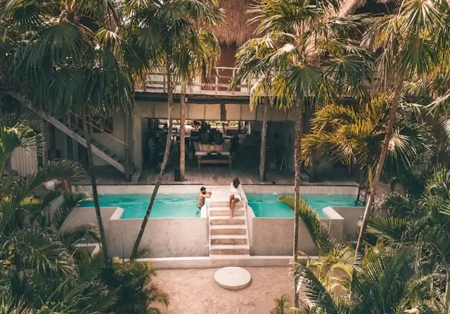 Couple relaxing by tropical resort pool surrounded by palm trees on romantic getaway