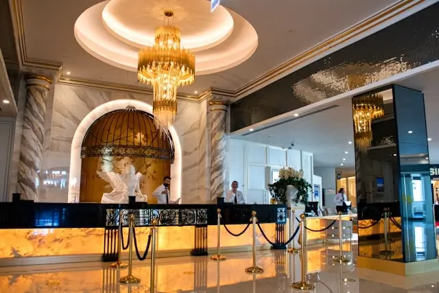 Elegant hotel lobby with ornate chandeliers, marble columns, and professional staff demonstrating luxury hospitality and tourism service standards