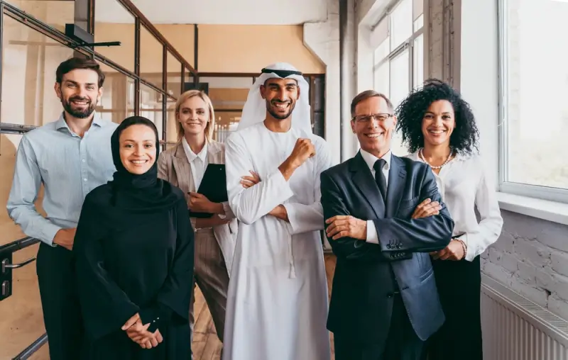 Multicultural business team including Emirati and international professionals in modern Dubai office space, showcasing diverse workforce in UAE companies