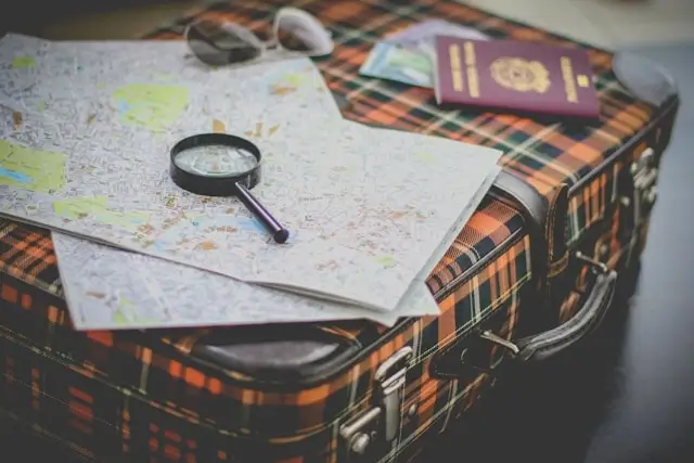 Travel map with magnifying glass and passport on vintage suitcase for road trip planning