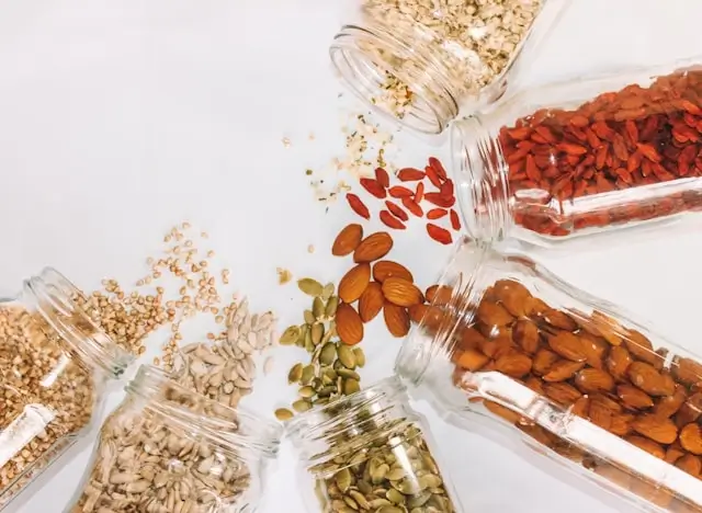 Variety of nuts and seeds spilling from glass jars, showing jaw-friendly foods that help stimulate healthy tooth development