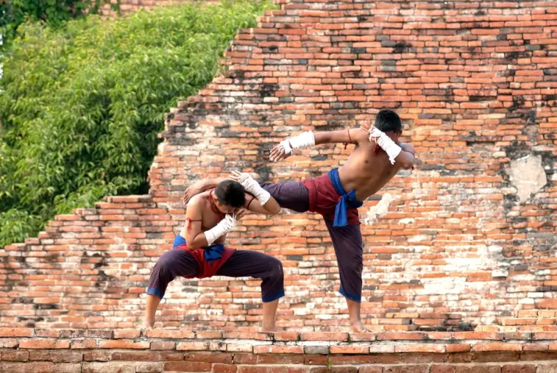 Two men practicing Muay Thai martial arts training at ancient temple ruins in Thailand