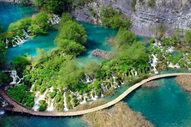 Aerial view of Plitvice Lakes cascading waterfalls and turquoise pools connected by wooden boardwalks, showcasing Croatia's premier Balkan hiking destination