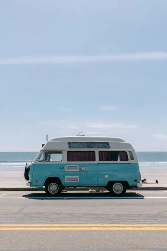 Vintage blue and white van parked by ocean representing mobile living and nomadic lifestyle with compact space solutions
