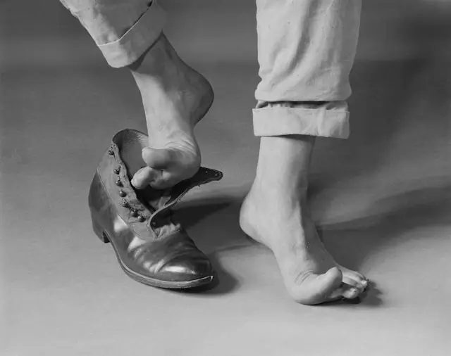 Person putting on leather walking shoes with laces in black and white photo showing proper shoe fitting