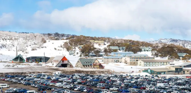 Thredbo village Australia in winter with snow-covered alpine lodges, ski facilities and parking area surrounded by frosted eucalyptus trees