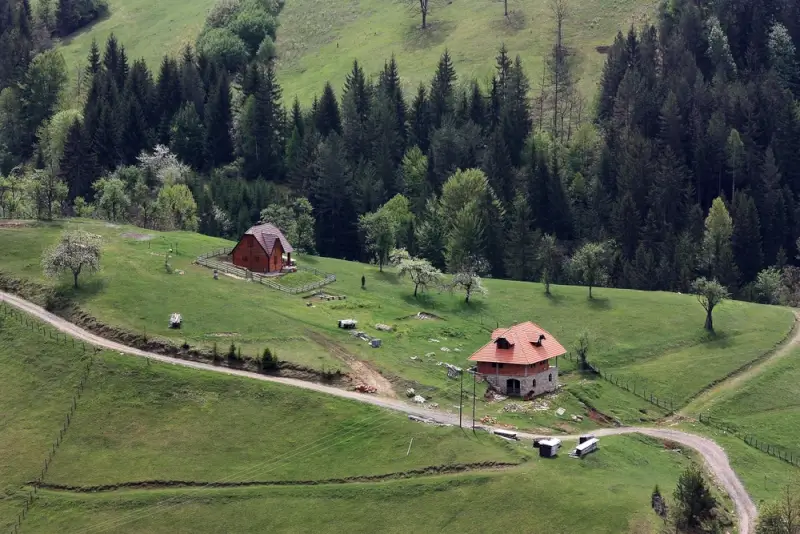 Traditional rural houses nestled in green rolling hills and dense forests of the Balkans at Tara National Park, showcasing authentic countryside accommodation for outdoor adventure travelers