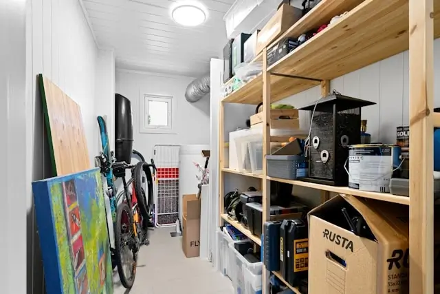 Organized storage room with wooden shelving units maximizing vertical space for belongings and equipment in small area
