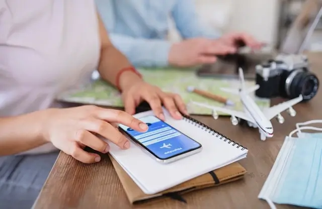 Digital nomad planning travel itinerary with smartphone, map, camera and airplane model for smart travel management and adventure planning