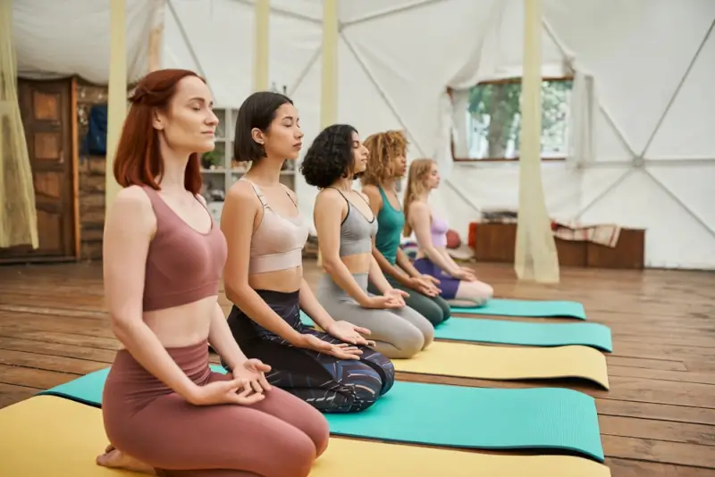 Group of women practicing breathwork meditation in peaceful retreat setting with yoga mats