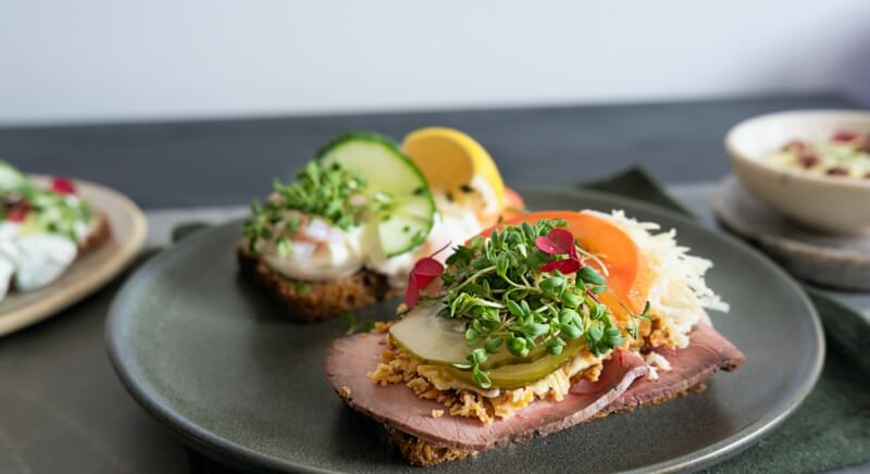 Danish smørrebrød open-faced sandwiches with roast beef, microgreens, and fresh toppings on dark rye bread, traditional Denmark cuisine