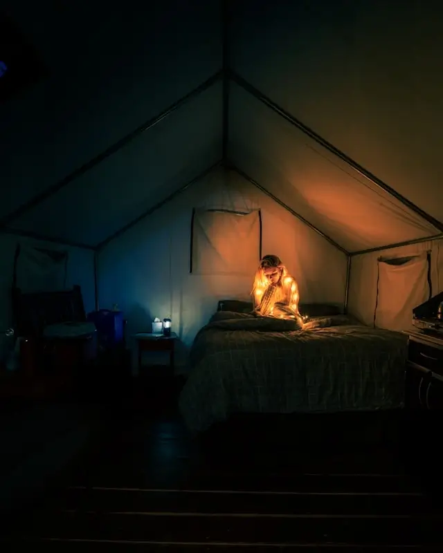 Cozy Coody tent interior with camper reading by warm lighting, showcasing spacious camping tent design with standing room and comfortable sleeping area