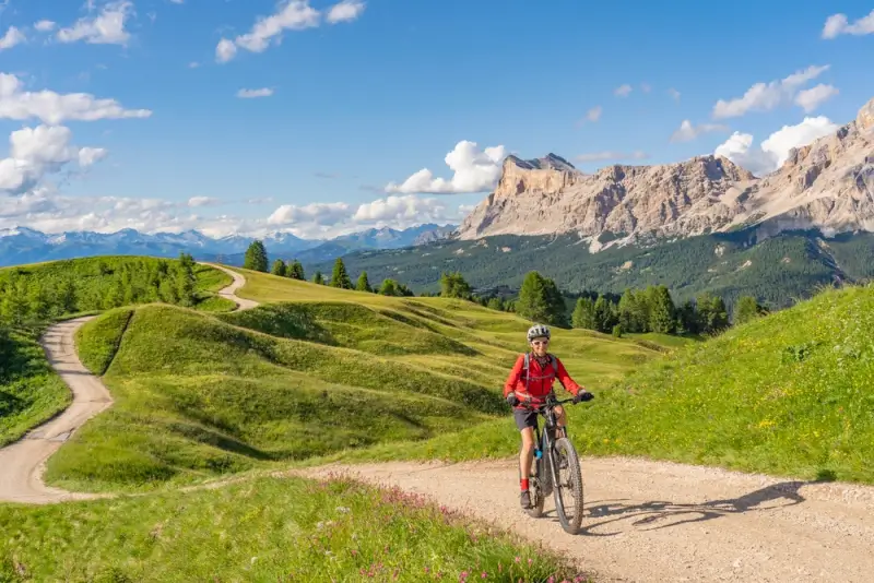 Cycling in Italy through the Dolomites with cyclist on mountain bike enjoying Alpine passes and dramatic limestone peaks in Northern Italy