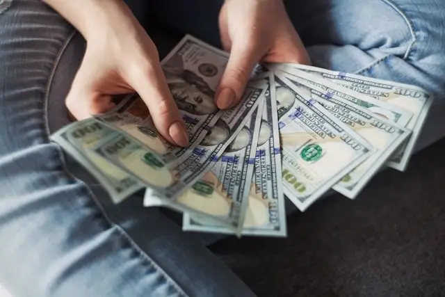 Woman's hands holding US dollar bills for solo travel budget planning and cash management
