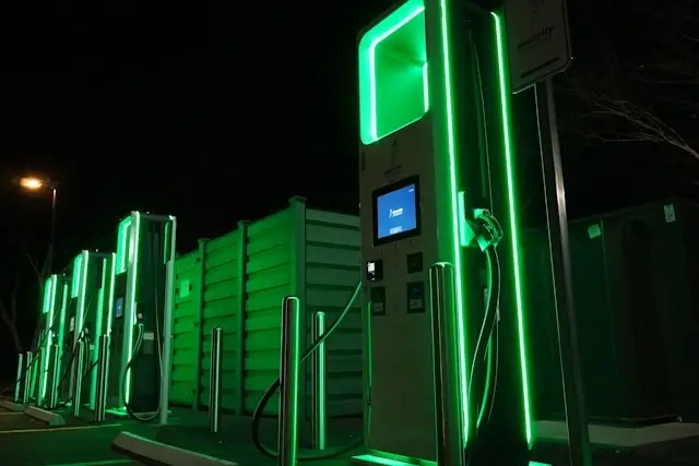 Electric vehicle charging station with green LED lighting at night showing modern EV infrastructure